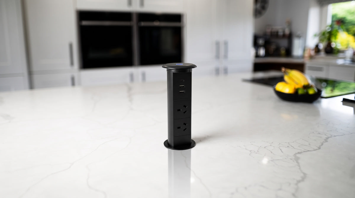 V3L pop-up socket raised through a white marble kitchen island